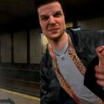 An image showing a screenshot from Max Payne 1 featuring Max squinting and shooting a gun.