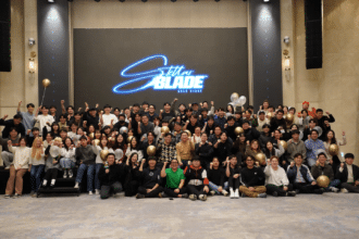 An image showing a group of people posing for the photo in front of a display showing Stellar Blade graphics.